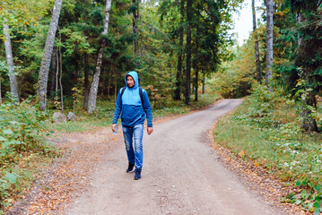 A middle age male hiking with a backpack.Man walks along the autumn forest path way.A healthy lifestyle in nature.