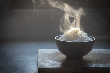 Cooked rice with steam in black bowl on dark background,hot cooked rice in bowl selective focus,hot...