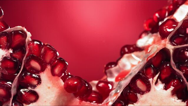 Pomegranate Splits in half and Grains rolls down with juise splash in slow motion
