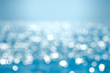 Delicate blue texture bokeh sea. Summer background. Blurry blue bokeh glare on the water on a sunny day. Concept travel.