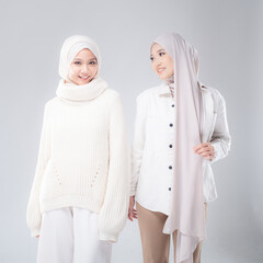 Portrait of two beautiful Muslim young women wearing modern and stylish casual wear with hijab isolated from studio background. Modern hijab fashion and beauty concept