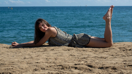 Woman lying on the sand on the beach looking at the camera