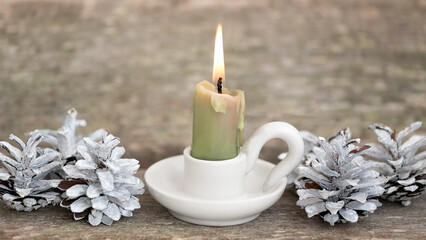 Obraz na płótnie Canvas Christmas decorations candle on a candlestick and pine cones on a wooden background.
