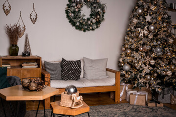 Christmas. Living room with grey sofa, armchair, coffee table.  A Christmas tree decorated for the new year. Gifts and decorations.