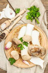 Fresh Pleurotus eryngii mushrooms on wooden background. Raw king oyster eringi with spices and herbs