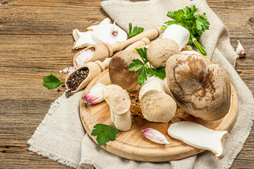 Fresh Pleurotus eryngii mushrooms on wooden background. Raw king oyster eringi with spices and herbs