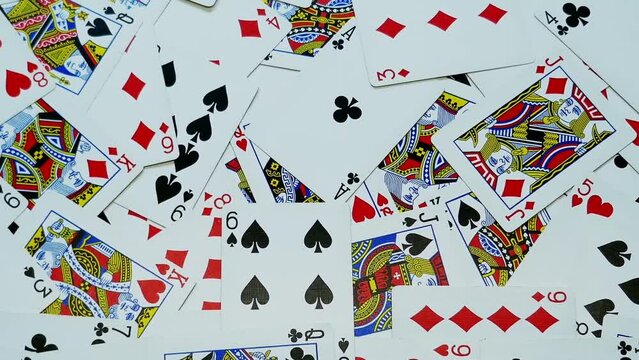 Randomly placed playing cards , scattered on a table from a playing deck , smooth motion from left to right , close up.