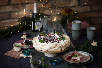 Christmas cake Pavlova with berries decorated on dark blue background with Christmas decoration
