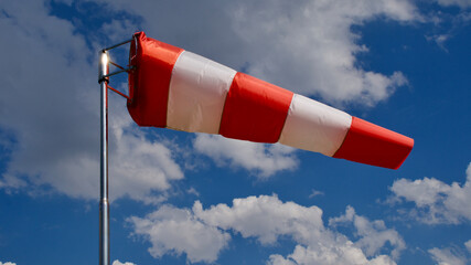 Windsock. Windsock flag. Wind direction indicator. Wind intensity. Windsock in front of blue sky.