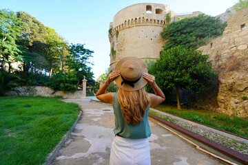 Tourism in Calabria. Back view of beautiful woman in Crotone with Charles V Aragon Castle in...