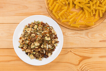 Spices and dried vegetables mixture and spiral pasta, top view