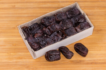 Soft date fruits in cardboard box on a wooden surface
