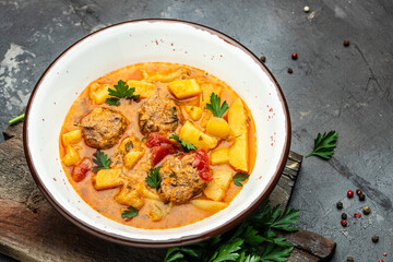stewed vegetables with meatballs in a white bowl, place for text, top view