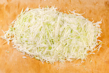 Shredded white cabbage on the large wooden cutting board