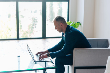 Businessman sitting in an office working with a laptop computer. Business man portrait.	