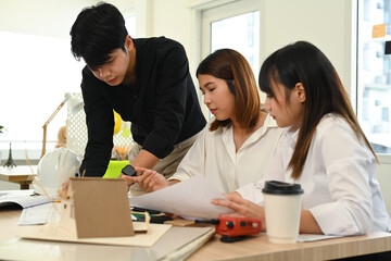 Group of young people working together of architectural project, collaborating with team leader at creative office