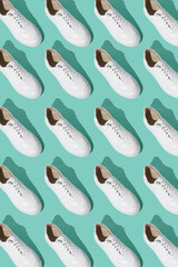 White sneakers pattern on a mint blue background. The shoes are comfortable and casual. Background for a shoe store. A pair of new sneaker shoes.
