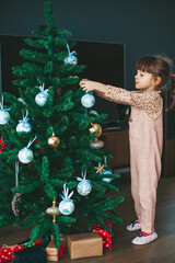 Little girl hanging ornaments on a Christmas tree