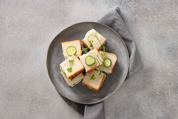 Homemade English tea cucumber sandwiches with ricotta and dill on gray background. Crispy freshness cold british summer appetizer.