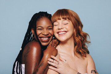 Cheerful young women with different skin tones smiling while standing together
