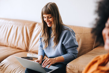 Cheerful young businesswoman using a laptop in a lobby
