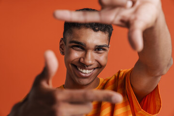 Young black man with piercing laughing while making frame gesture