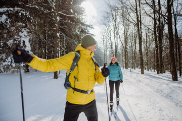Senior couple skiing together in the middle of forest
