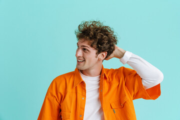 Young handsome stylish curly smiling man holding head looking aside