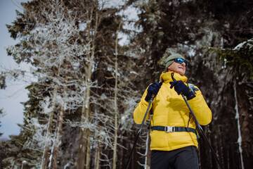 Fototapeta na wymiar Low angle view of senior man admiring nature during cross country skiing.