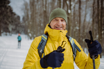 Senior man admiring nature during cross country skiing in forest.