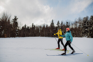 Senior couple skiing together in the middle of forest