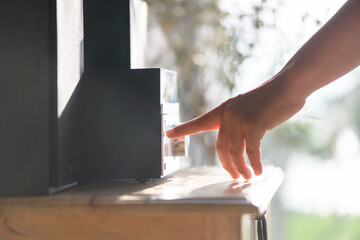 Woman hand turns on and listening to music via the Hi-Fi stereo in her home. Close up