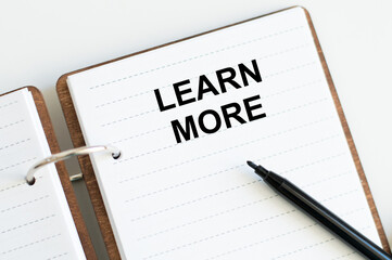 LEARN MORE text on notebook with a black marker on a light background. BUSINESS CONCEPT