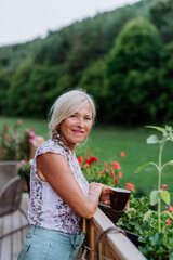 Senior woman resting on her terrace with cup of coffee and enjoying view at forest.