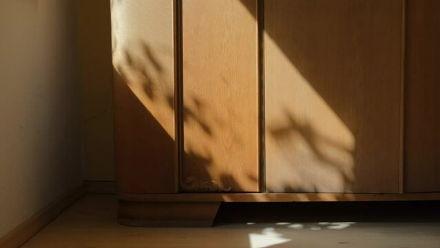 An antique wooden cabinet with patterns in a room near a window on a sunny day. Close-up.