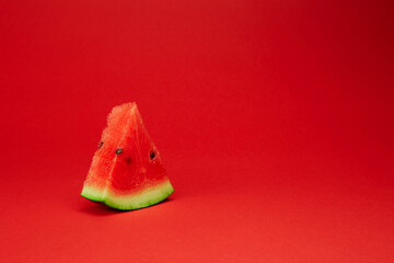 Fresh ripe watermelon slice isolated on the bright solid red fond background