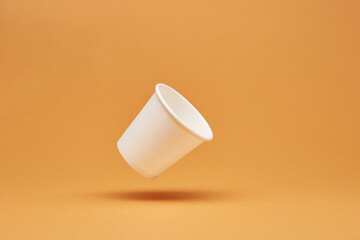 Disposable white single one recyclable cardboard paper cup floating above the surface isolated on...