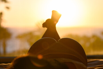 Naked beautiful woman in panties lying on the bed against sea and palm trees at summer sunny day