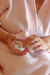 A senior woman picking up a pill out of a medicine pot which is on her lap.