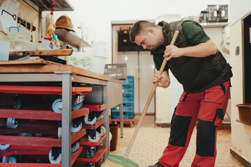 Man with down syndrome sweeping restaurant kitchen. Concept of integration people with disabilities...