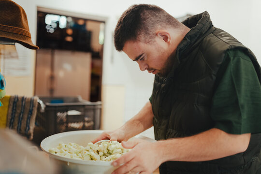 Man with down syndrome working in kitchen in zoo, prepairing food for animals.Concept of integration people with disabilities into society.