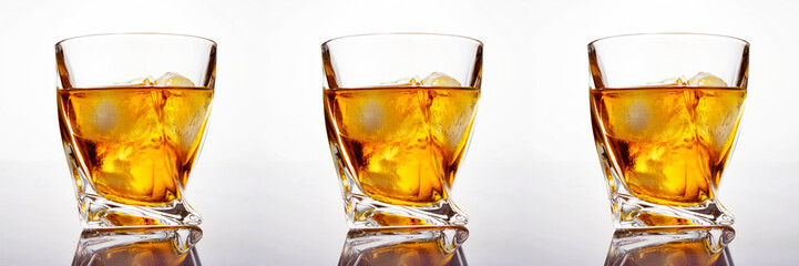 Glass of scotch whiskey with ice on a white background, close-up