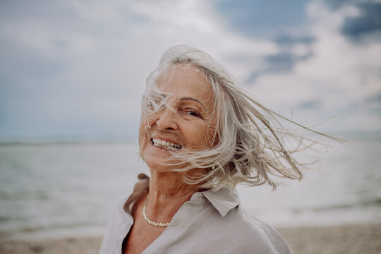 Portrait of happy senior woman with wind in hair, near sea.