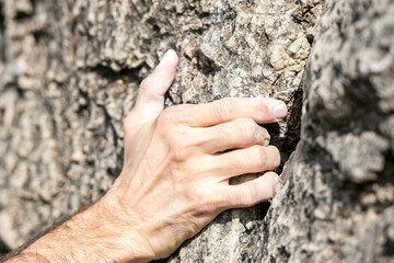 Detail of the fingers in tension of a climber clinging to a rock with magnesium