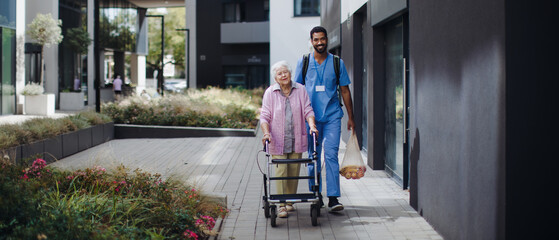 Happy caregiver caming back from grocery with his senior woman client.