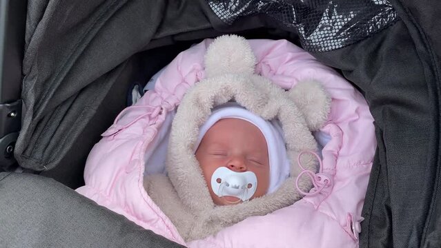 Child girl in a stroller with a pacifier vortu walks outdoors with her family in autumn. Newborn sleeping