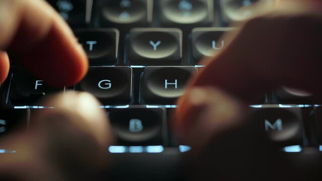 Close up footage of young businessman hands busy working, searching and studying by typing on glowing keyboard in the dark for send emails and surf on a web browser,