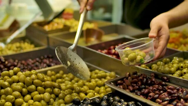 Vendor Scooping Various Salted Olives Into The Tub On The Mahane Yehuda Market in Jerusalem, Israel. - close up