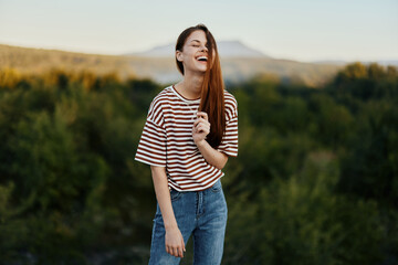 A young woman laughs and looks at the camera in simple clothes against the backdrop of a beautiful...