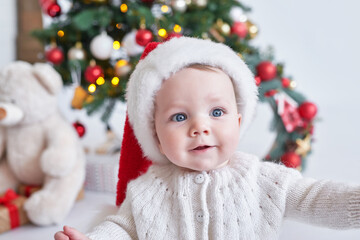 Santa baby. Christmas tree background. Happy New Year! Child in Santa's hat.